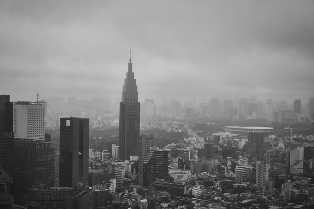 Black and white aerial view of Tokyo skyline with the NTT Docomo Tower rising through foggy cityscape of Shinjuku