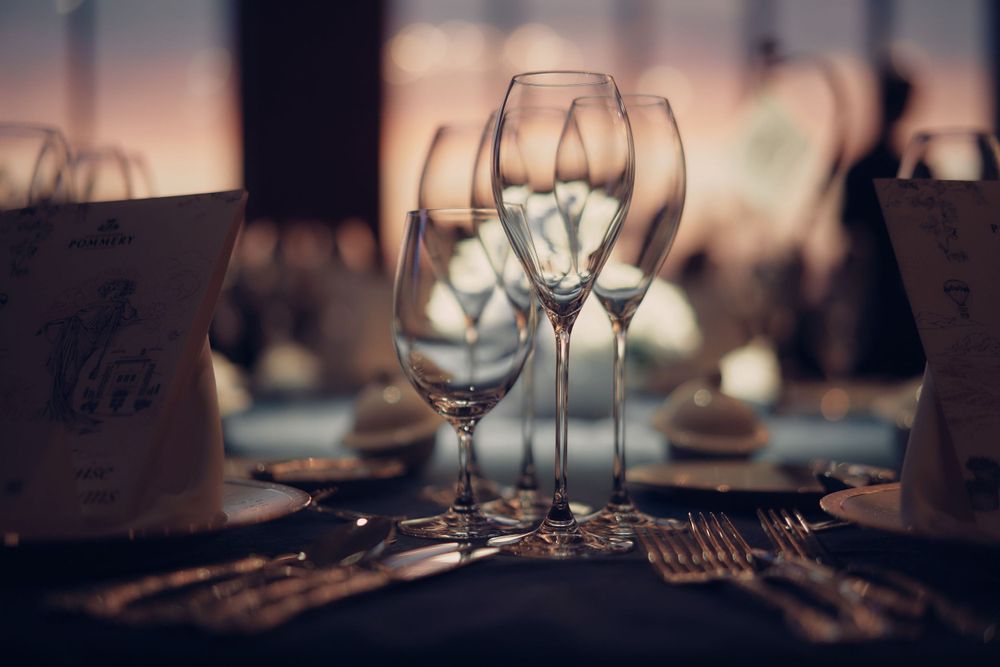 Empty wine glasses await diners at an elegant table setting with soft ambient lighting and blurred background with Pommery Champagne