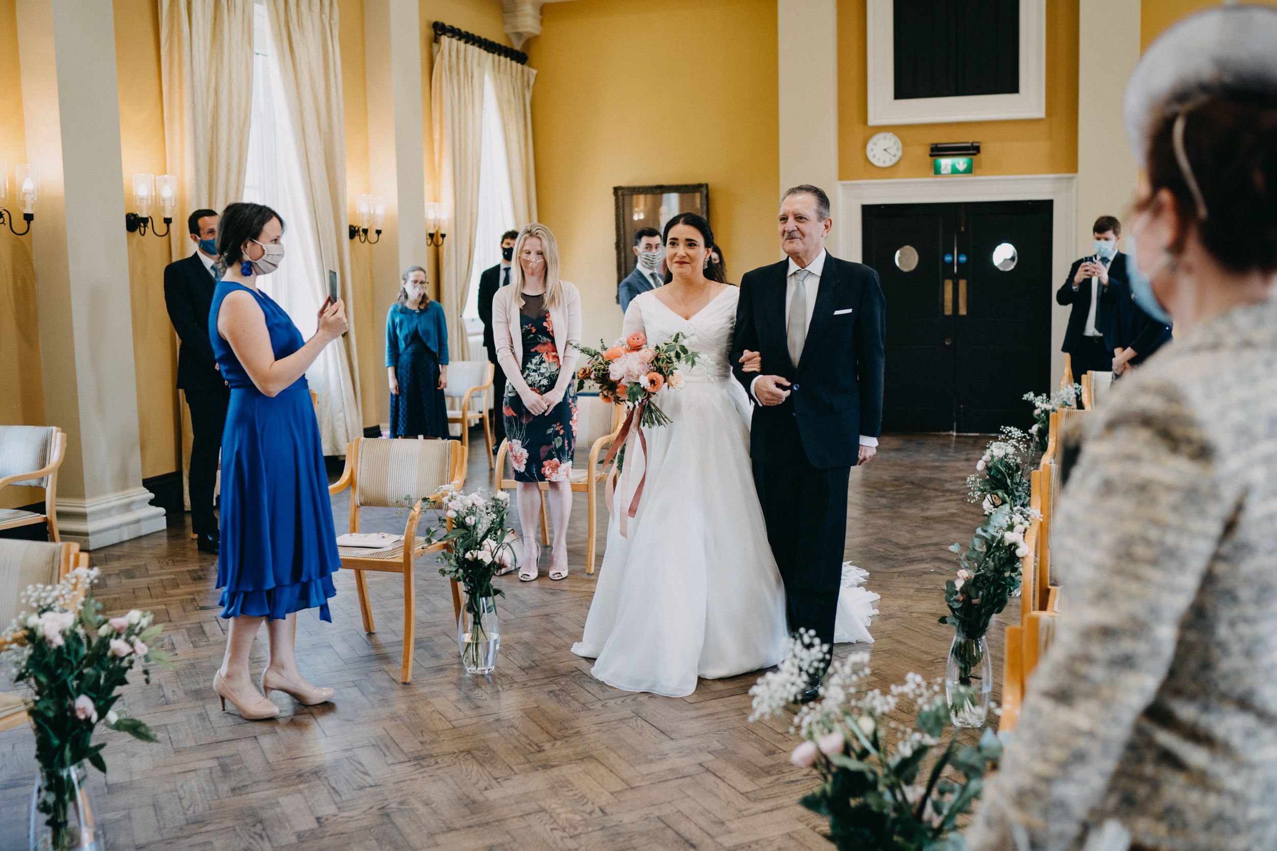 Wedding celebration in a warmly lit room with elegant floral decorations and draped fabrics.