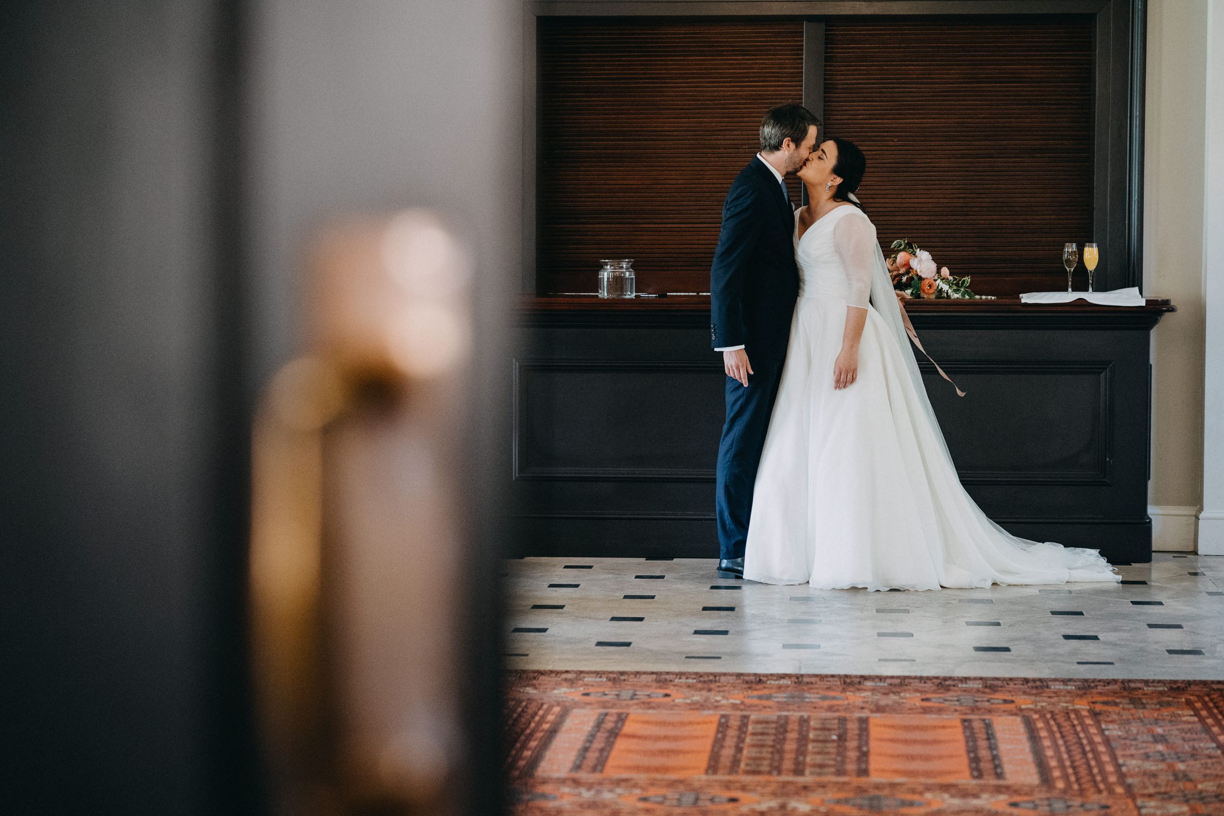 Intimate wedding moment captured through a doorway showing couple in traditional attire.