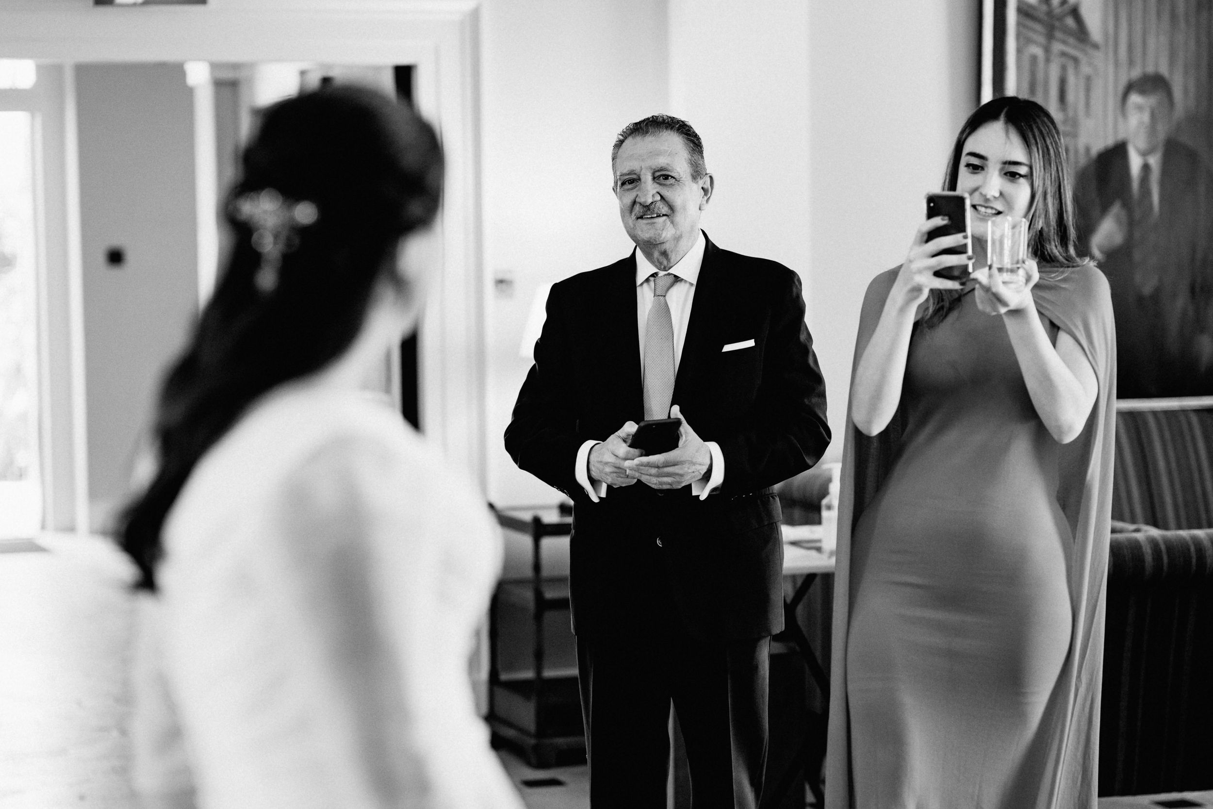 Wedding guests in formal attire react emotionally during a special moment at an indoor venue.
