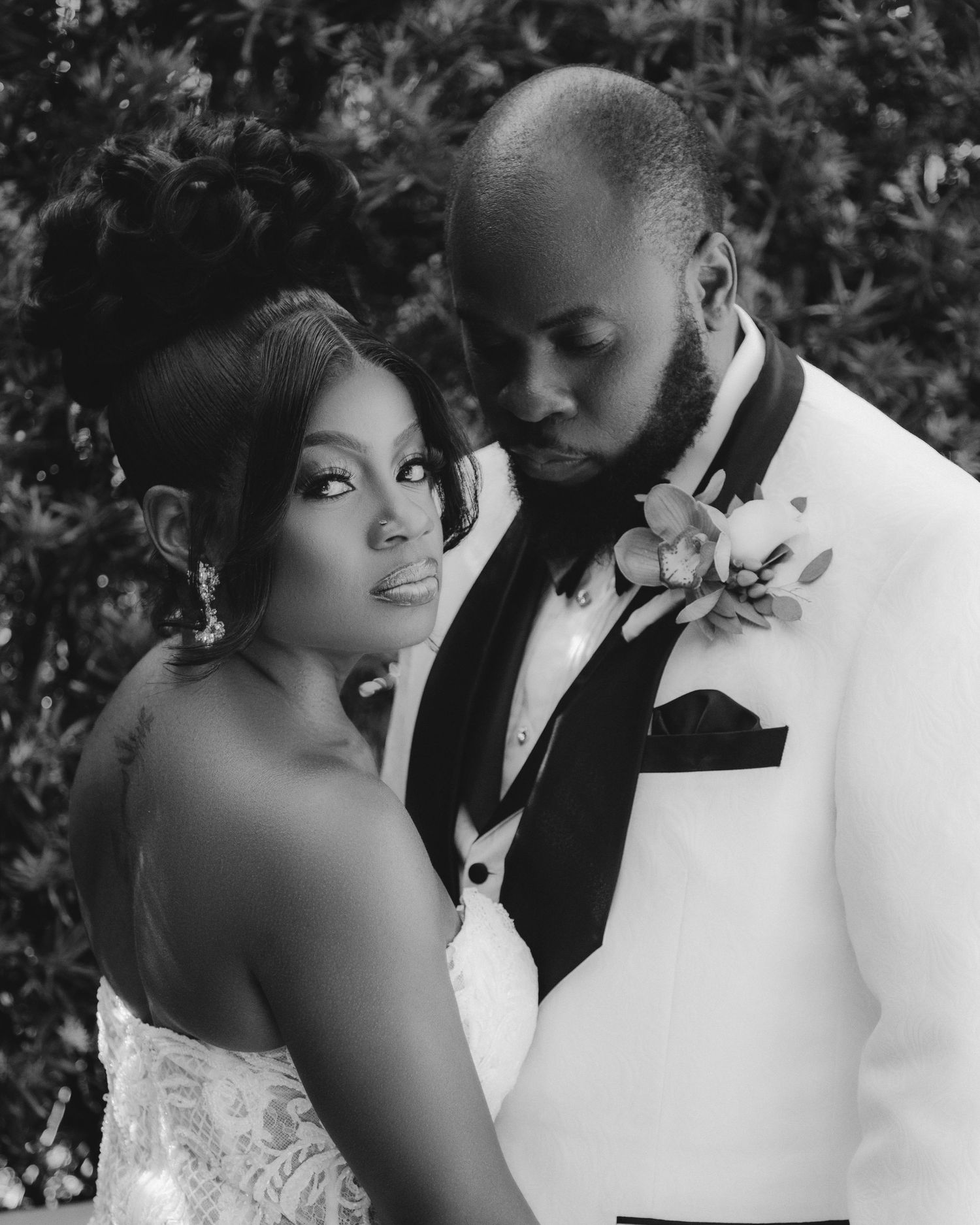 A black and white portrait of newlyweds in elegant wedding attire.