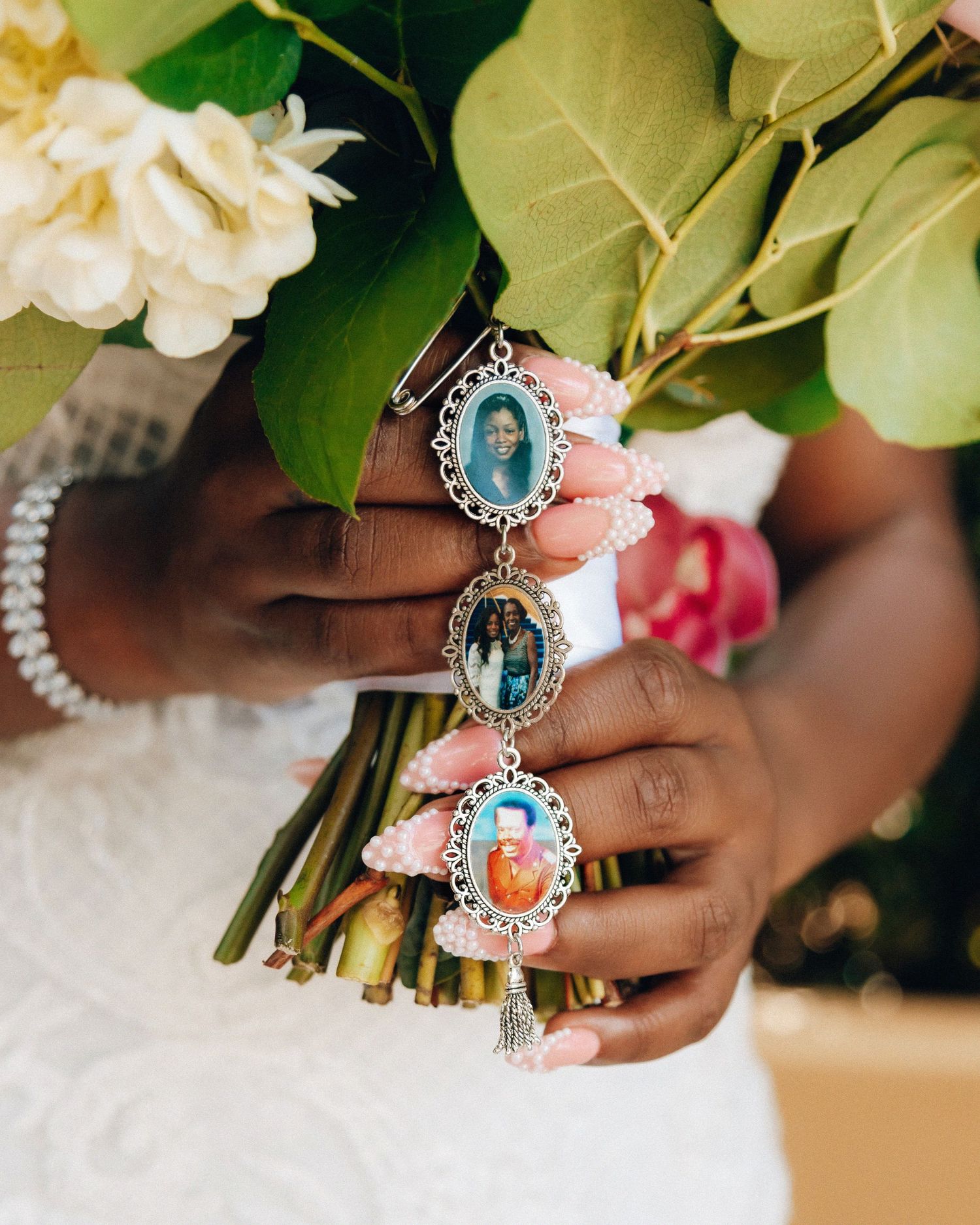 Close-up of hands holding a bridal bouquet adorned with ornate blue and silver jewelry.