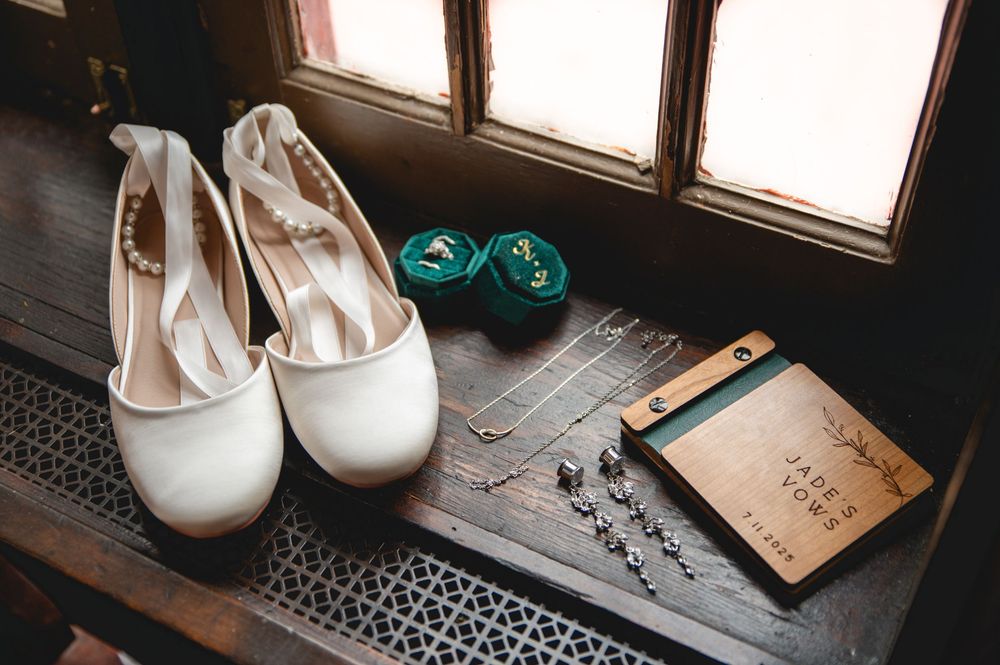 White bridal heels and wedding accessories arranged on a rustic wooden floor with teal accents.