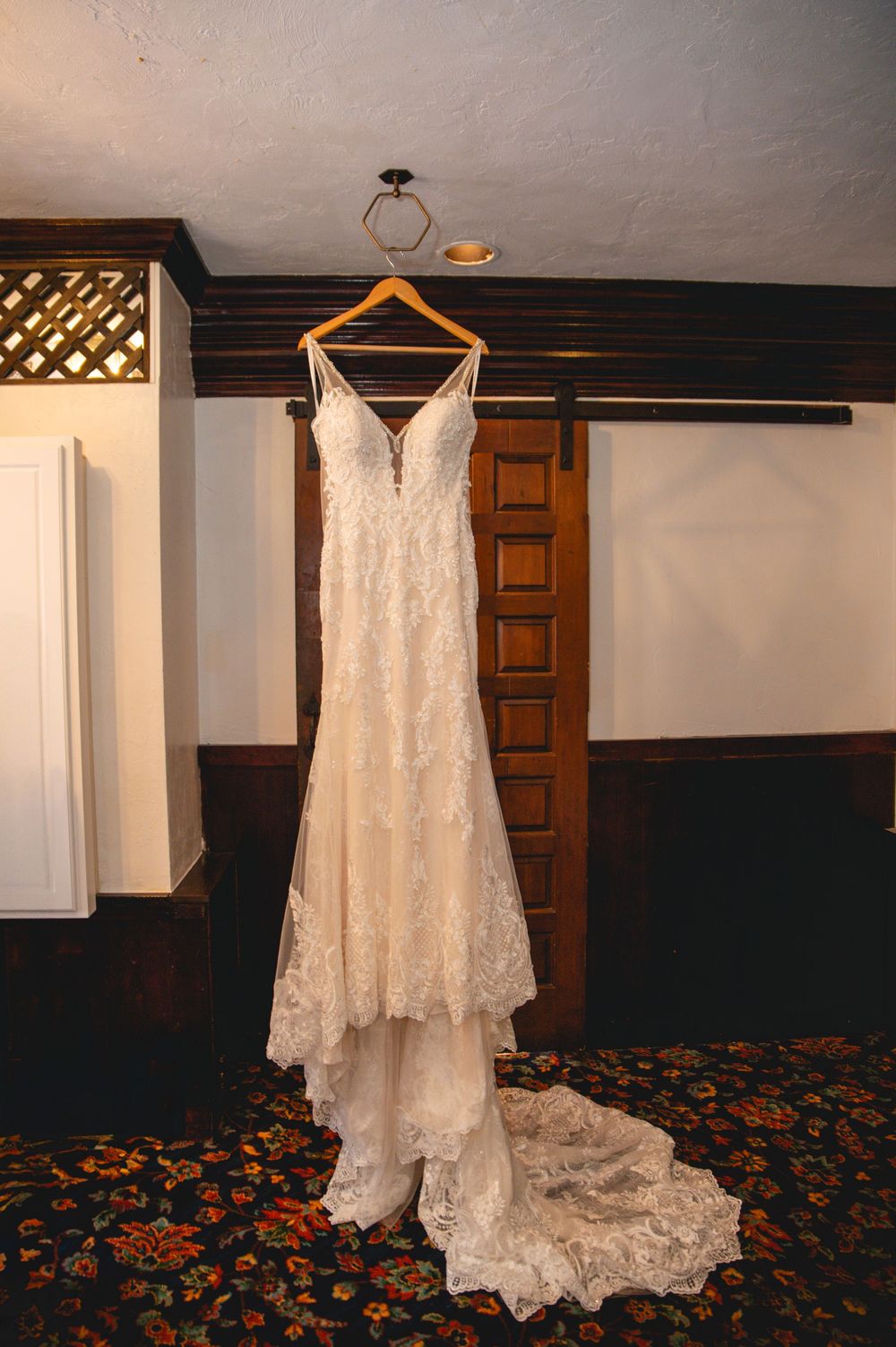 Five identical photos of an elegant lace wedding dress hanging on a wooden hanger against a dark wood-paneled wall.
