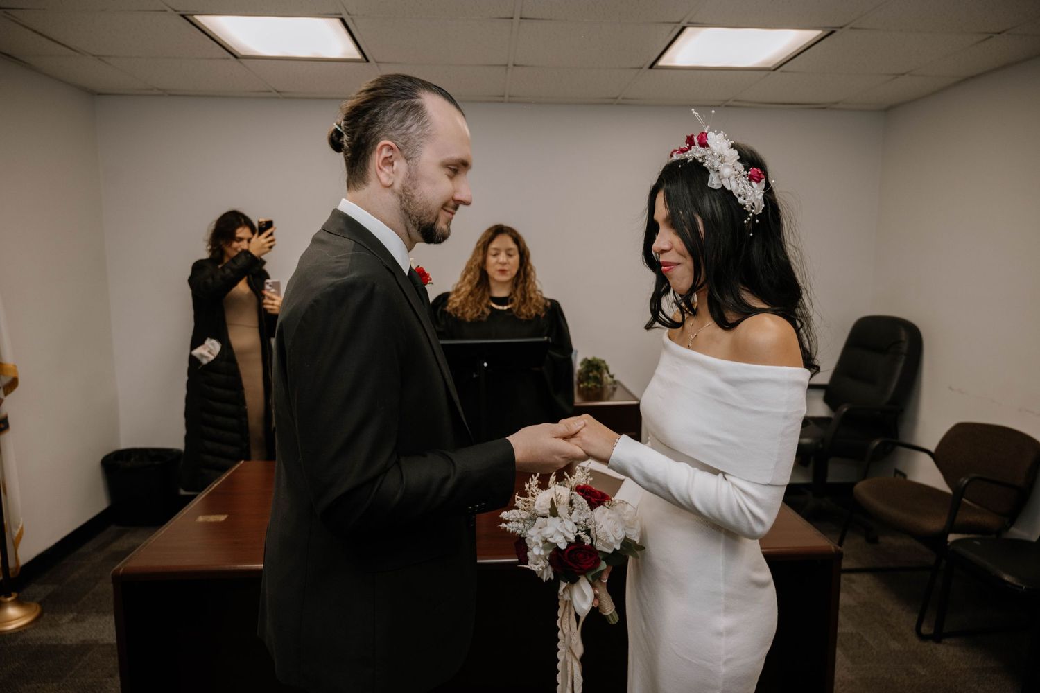 Wedding ceremony documents being signed in a bright indoor venue with warm lighting and formal attire.