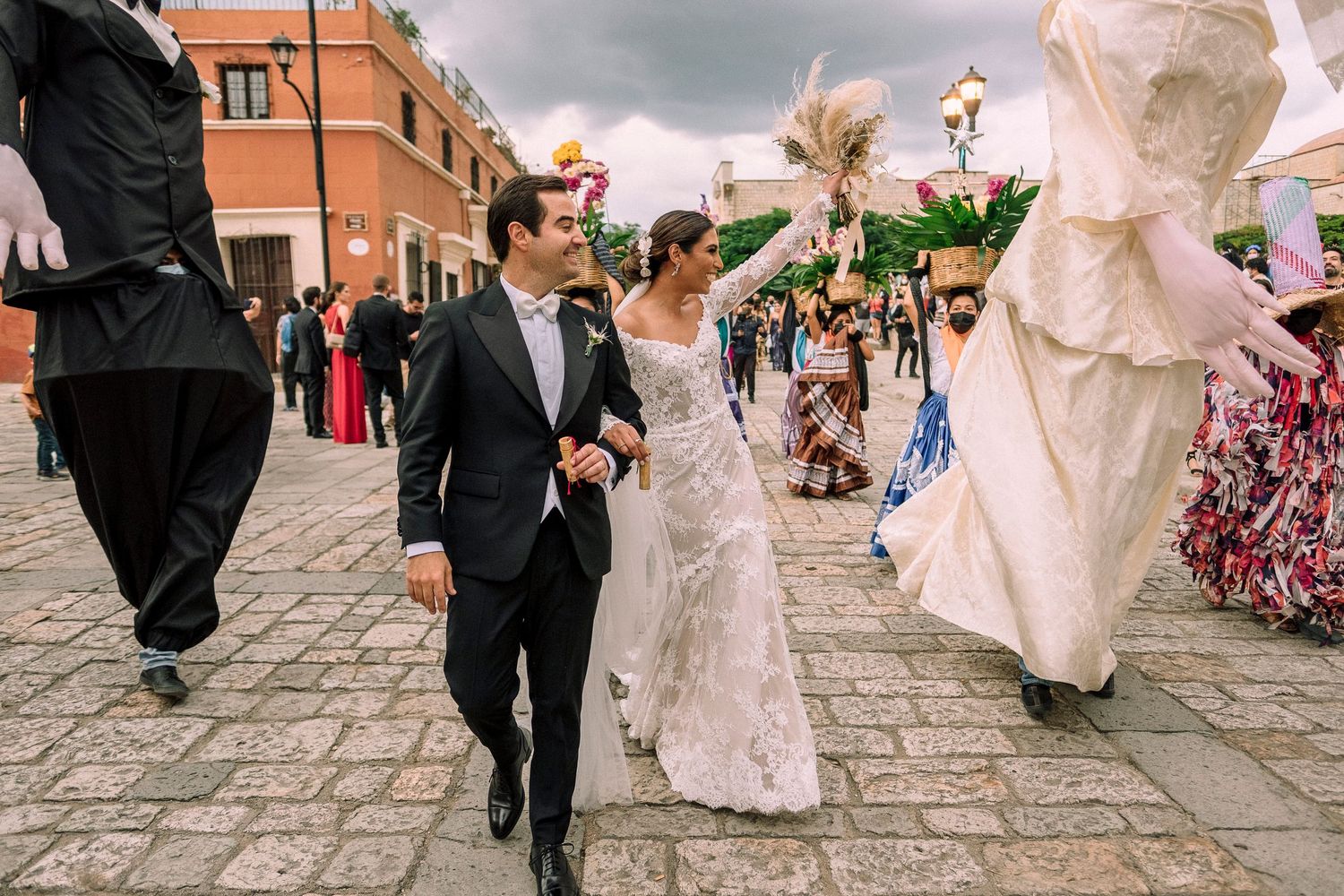 A joyous wedding party celebration in motion walking down cobblestone streets with decorative dancing and movement.