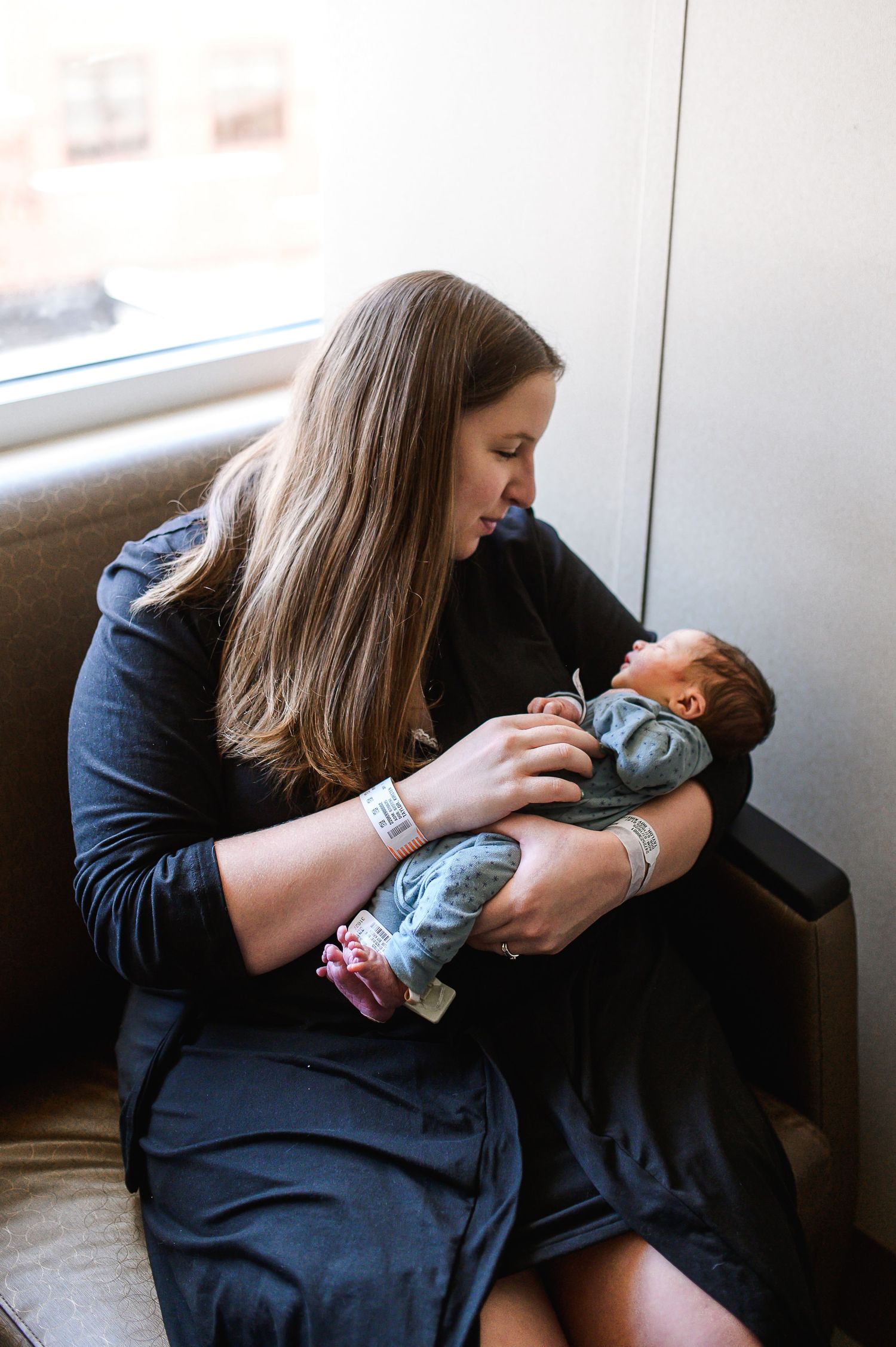 A mother holds and lovingly gazes at her sleeping newborn baby in a series of candid black and white photos.