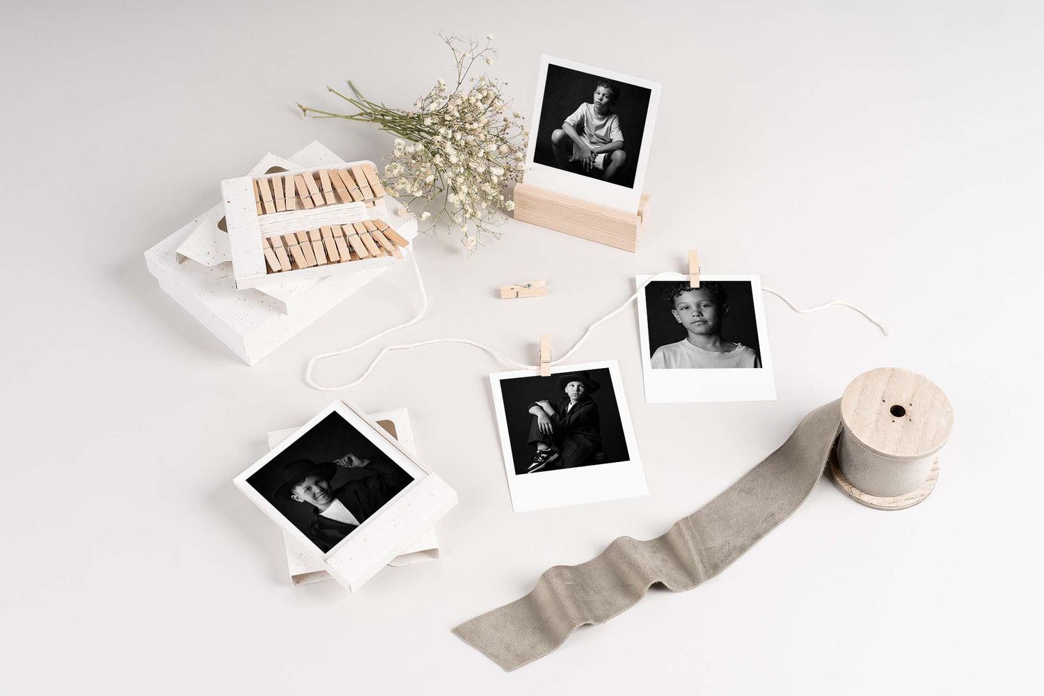 Black and white film photo prints and a roll of film arranged artistically on a white surface.
