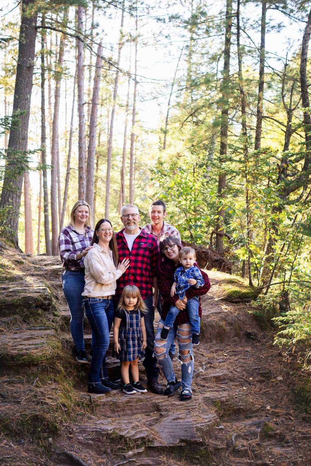 A group enjoying an autumn hike together on a sunlit forest trail surrounded by tall pine trees.