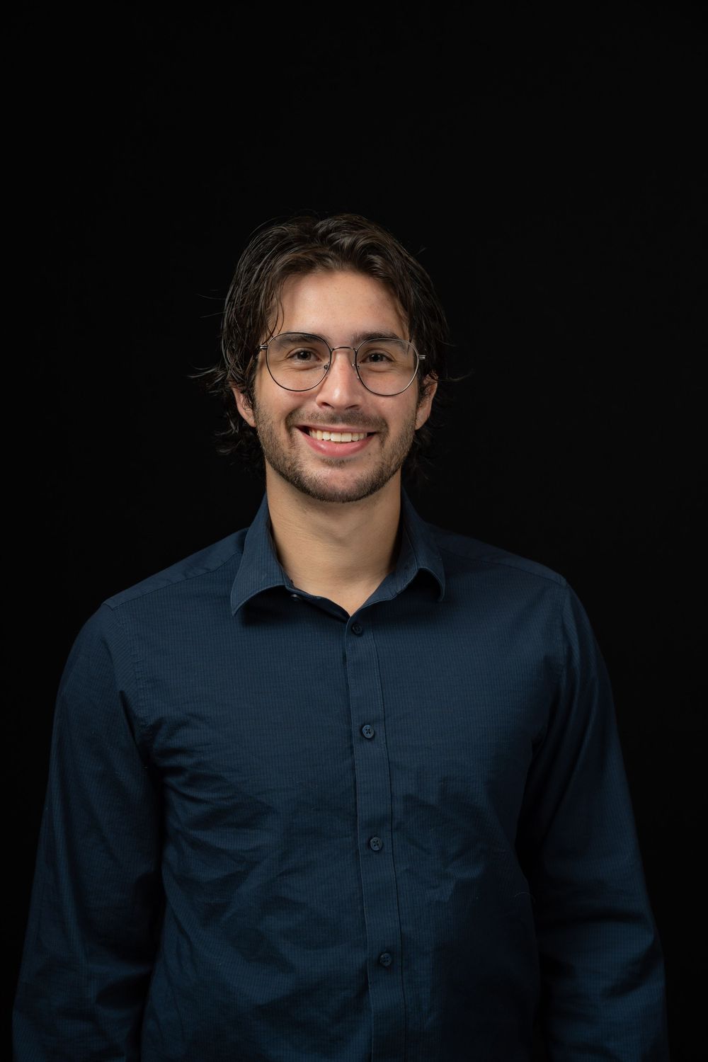 A series of professional headshots showing a person in a navy blue button-up shirt against a dark background.