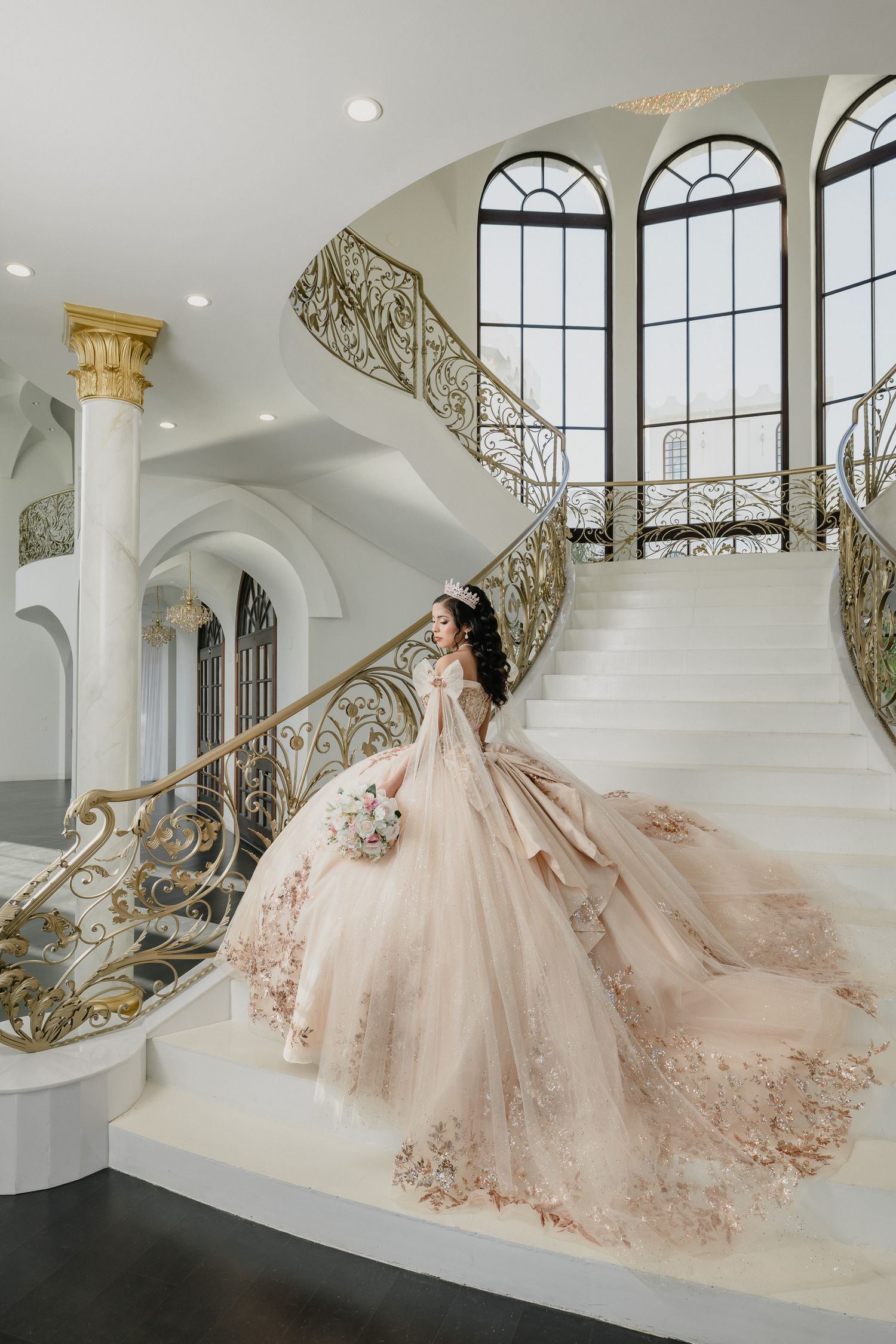 A princess ballgown with intricate lace details photographed on an elegant curved staircase.