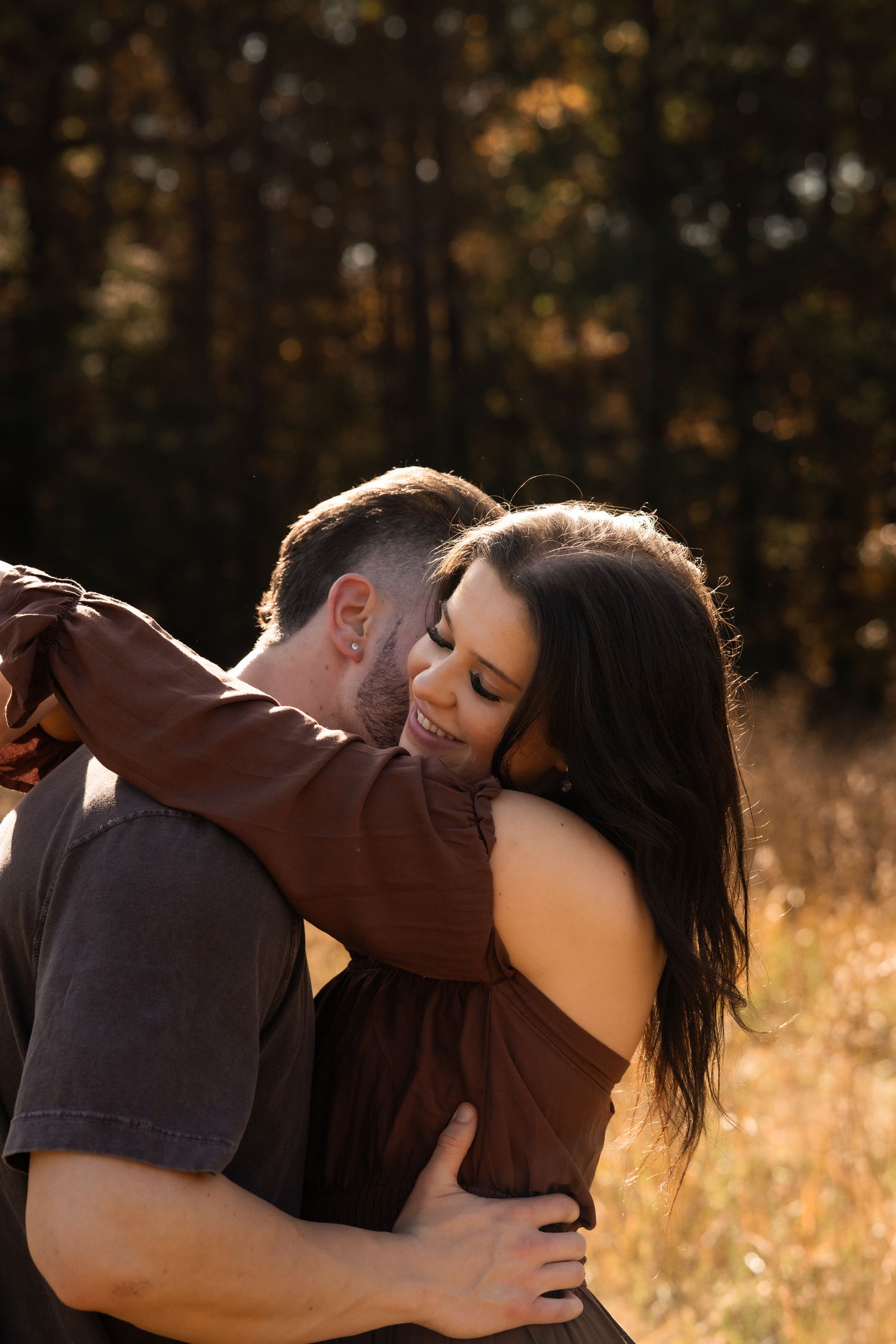 Intimate couple sharing tender moment in brown outfits against autumn backdrop.