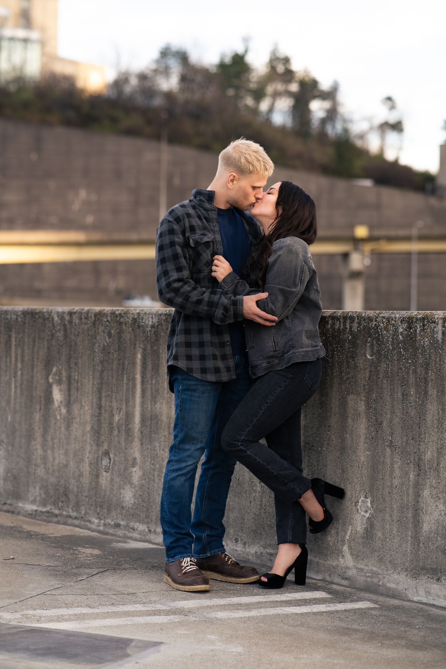 Romantic moment shared against concrete wall in urban setting at dusk.