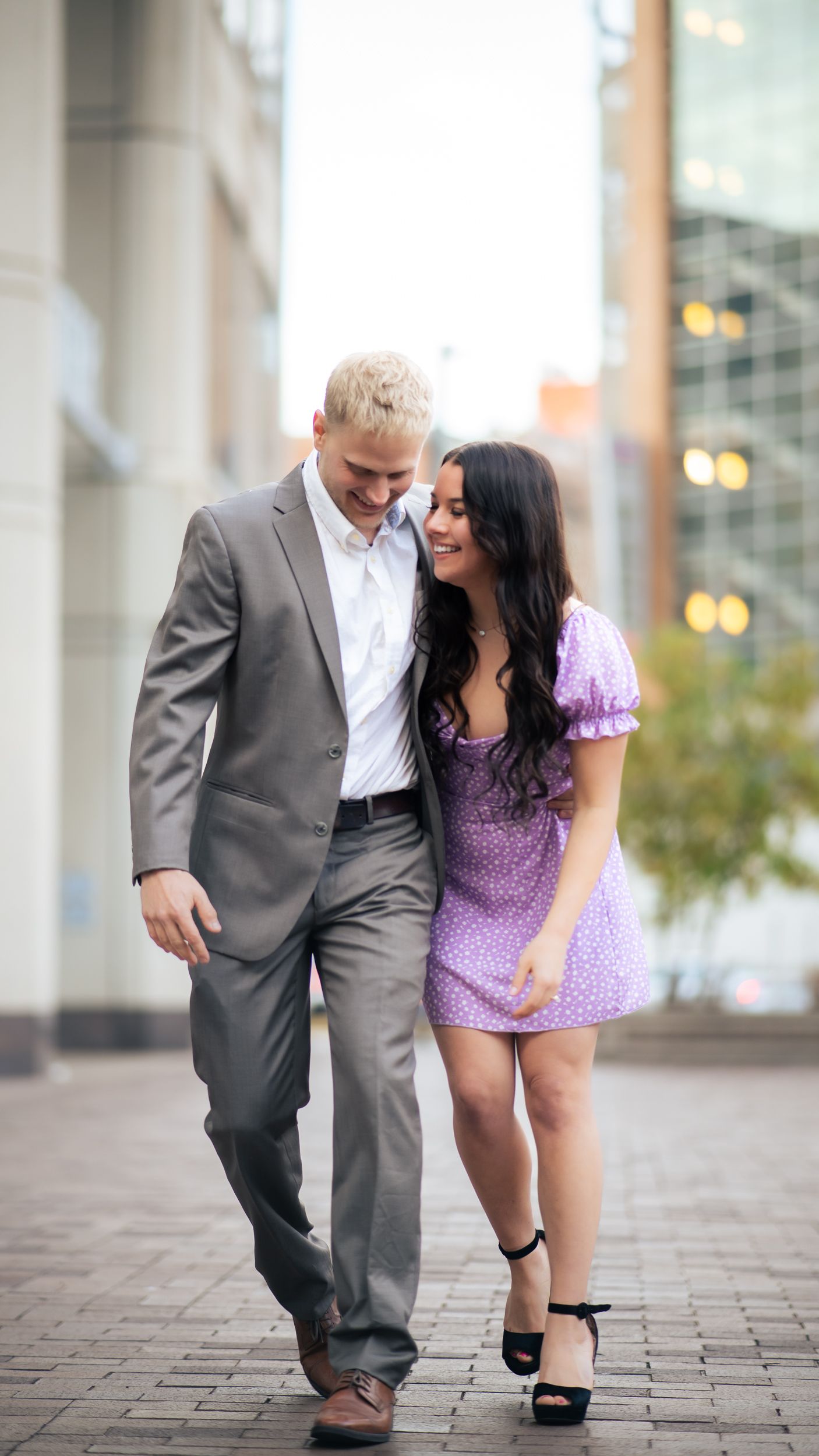 Couple walking together in urban setting, wearing coordinated formal outfits.