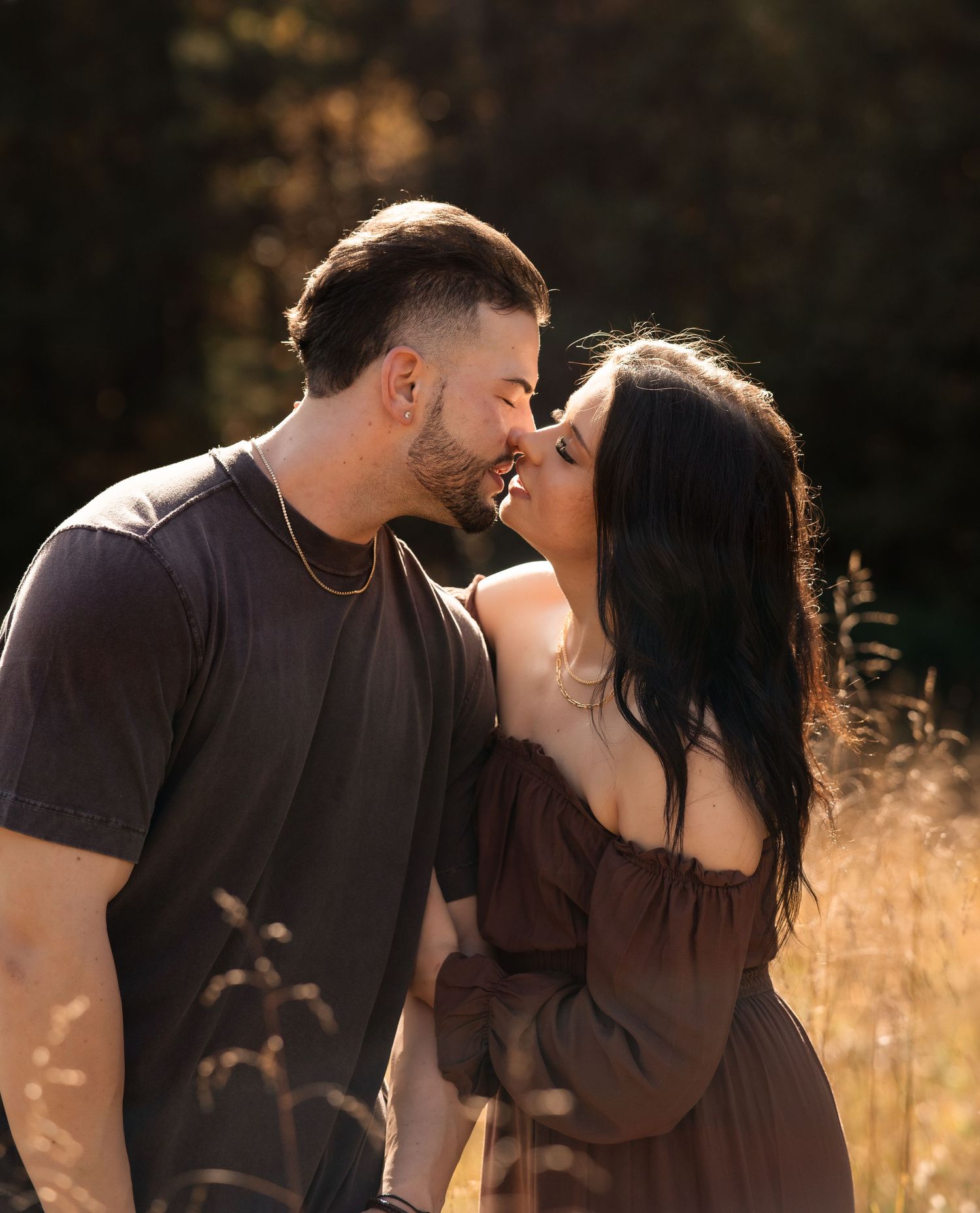 Intimate couple sharing a tender moment in golden sunlit field.
