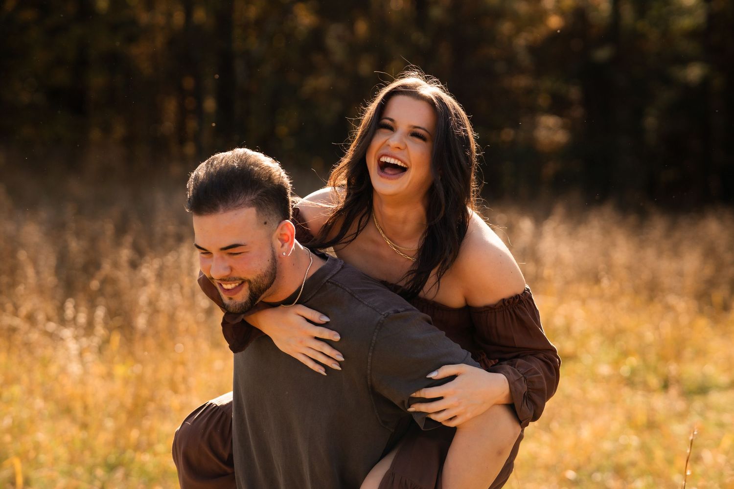 Joyful couple sharing playful piggyback moment in golden field.