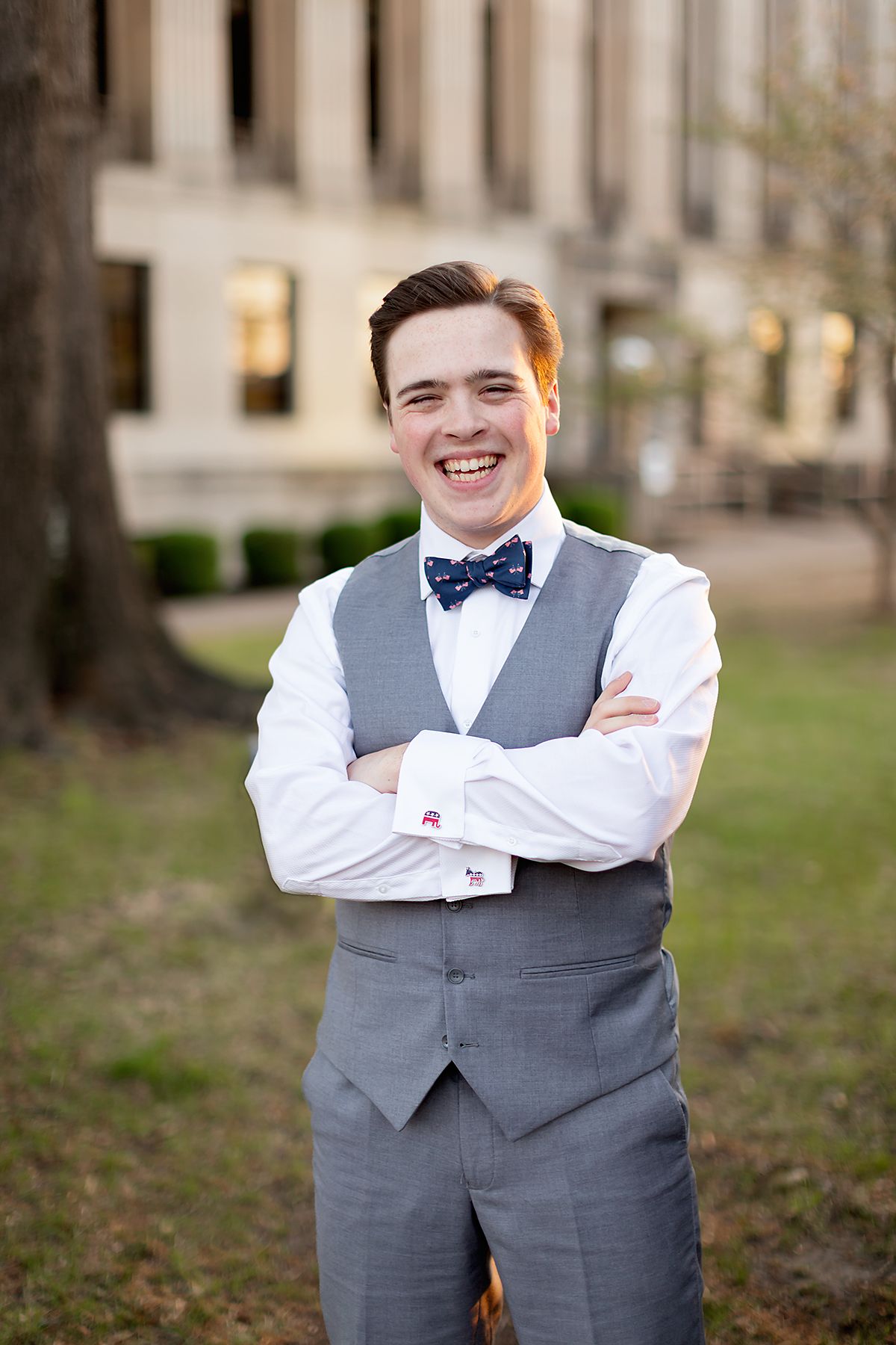 male with arms crossed, showcasing his political cufflinks, in downtown Jackson, TN. Senior pictures by MegMc photography.