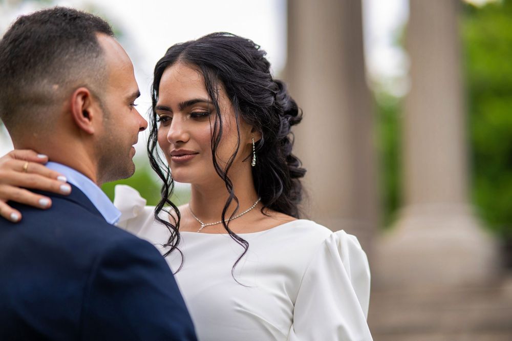 A romantic wedding couple embraces outdoors with soft lighting and elegant formal attire.