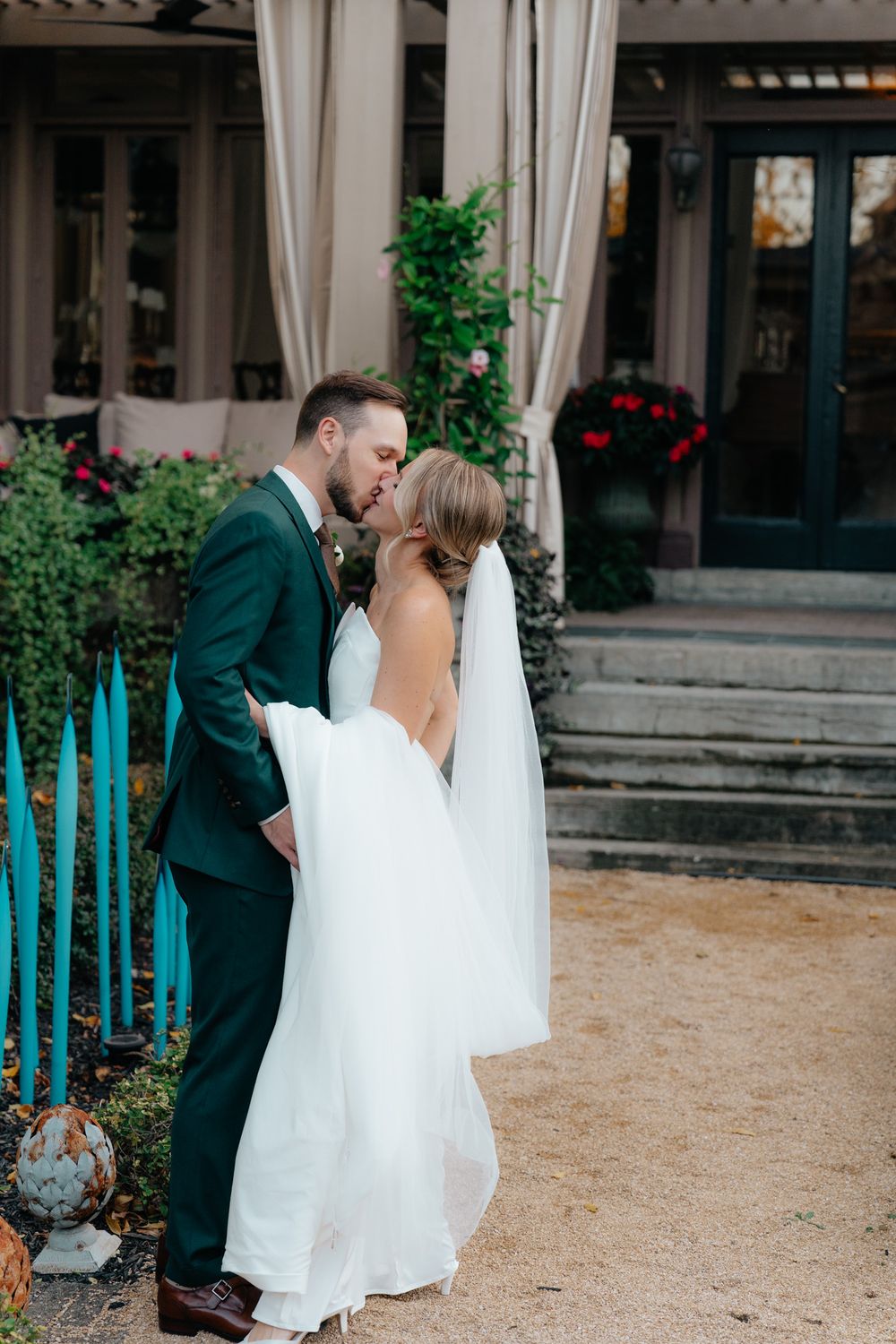 A romantic moment between newlyweds in front of a decorated garden venue surrounded by turquoise decor elements.