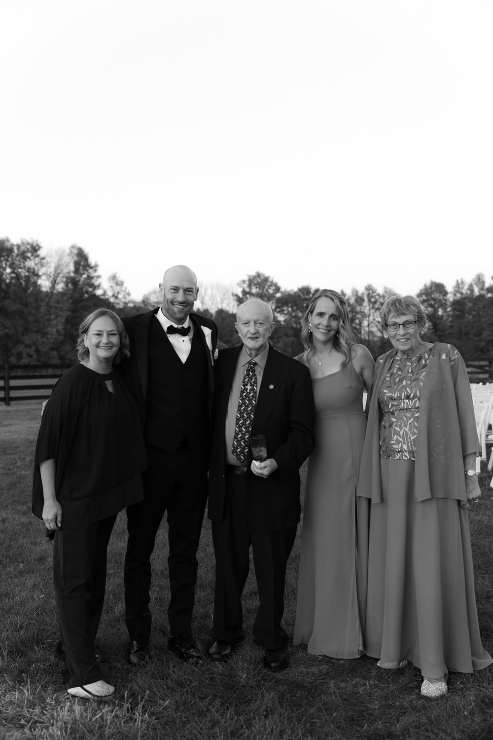 Family group of five people pose together at an outdoor wedding venue.