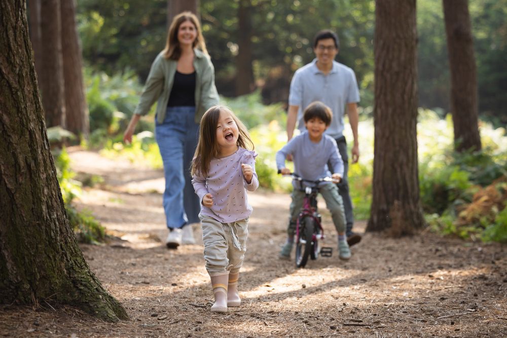 A happy family enjoys outdoor activities together while walking and biking on a wooded trail in the forest.