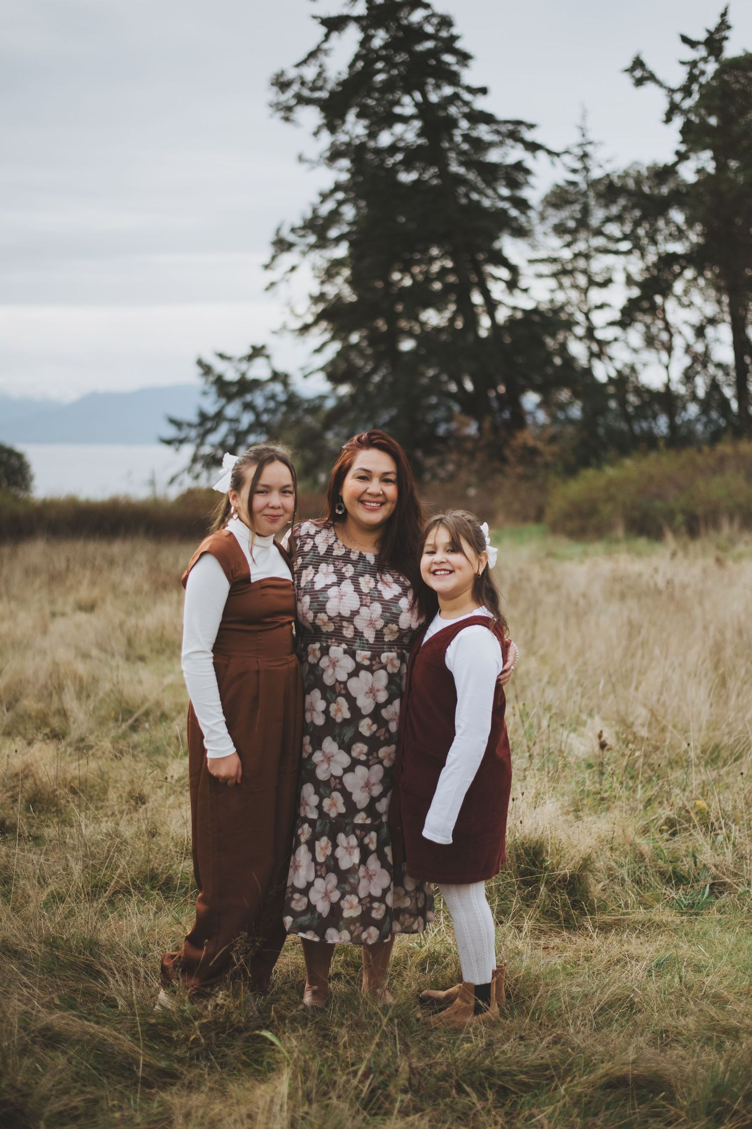 Mother and daughters standing together in a grassy field on Vancouver Island.