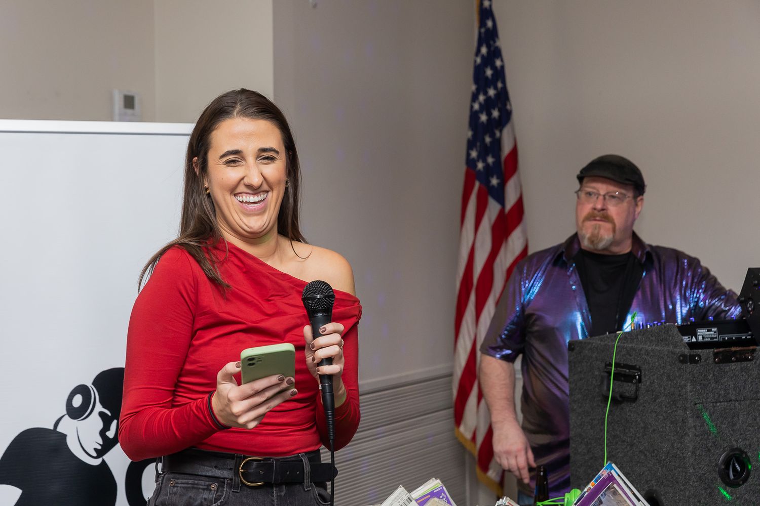 A speaker in red presents at a podium with American flag backdrop.