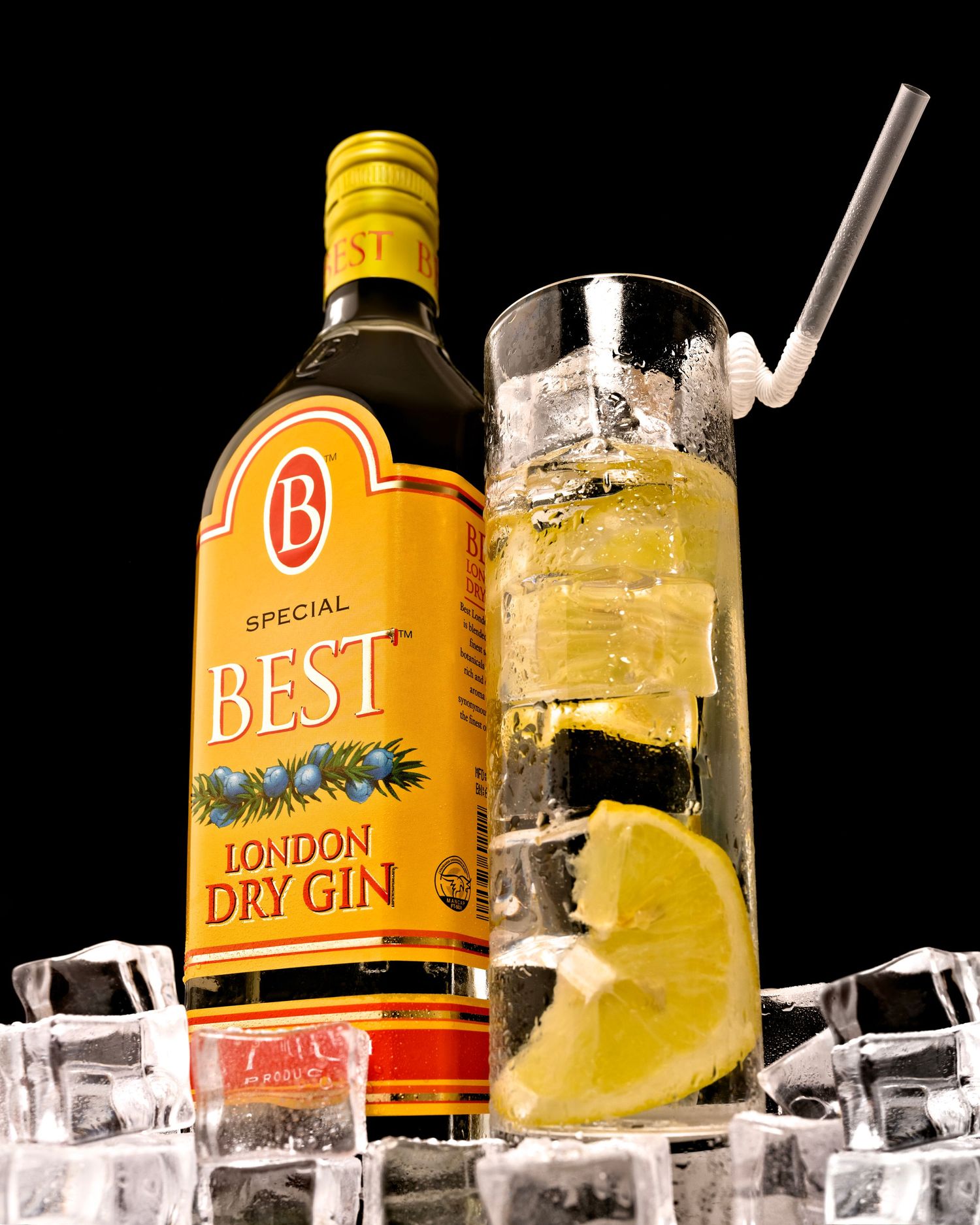 A bottle of Best London Dry Gin with a tall glass of gin and tonic garnished with lime and ice cubes on a dark background.