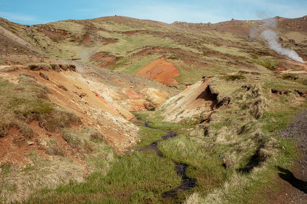 Geothermal landscape with colorful mineral deposits and steaming vents in KrýsuvÃk geothermal area, Iceland.