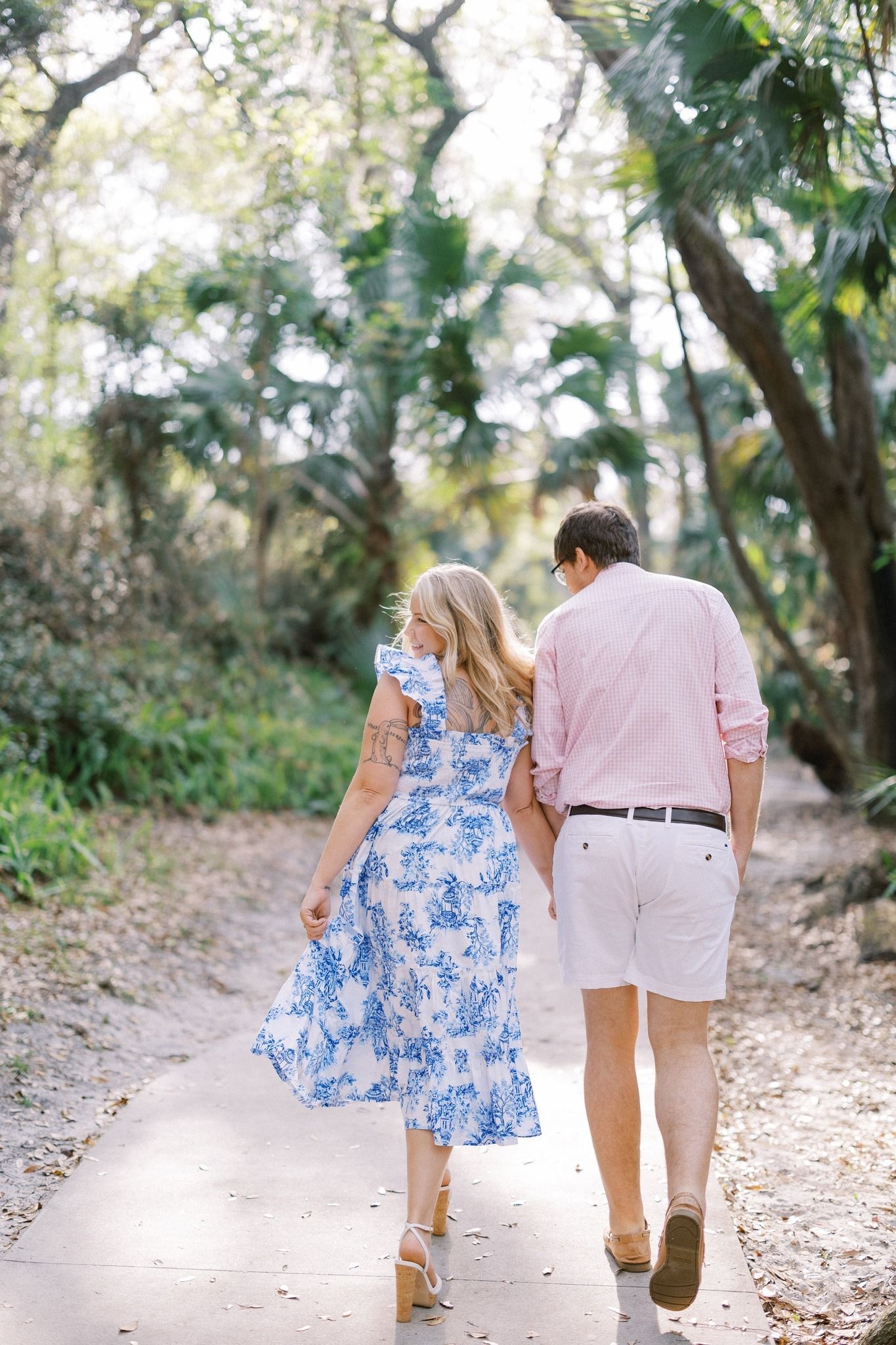 Couple walking along a scenic garden path surrounded by tropical foliage.