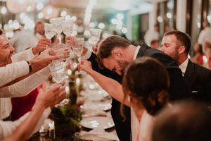 Wedding guests raise champagne glasses in a joyful toast at an elegant candlelit reception dinner.
