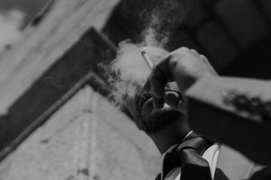 Candid groom portrait smoking before the ceremony — alternative wedding photographer style at The Astoria, Portugal.