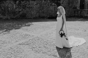 Bride walking alone with bouquet during sunset at The Astoria — candid portrait from a destination wedding in Portugal.