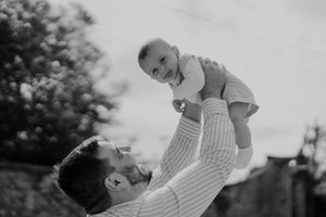 Father lifting his baby up during the cocktail hour — candid family moment at a destination wedding in Porto.
