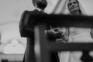Detail of hands during the wedding ceremony at The Astoria — intimate moment with the bride in the background.