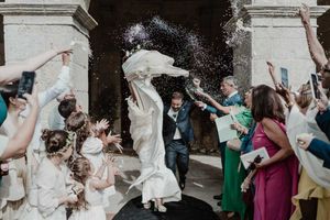 Colorful rice throwing as the couple exits the church — joyful moment captured in cinematic wedding photography at The Astoria.