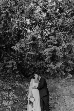 Bride standing under a boho-inspired tree arch — relaxed wedding portrait in the garden of The Astoria by Histórias com Alma.