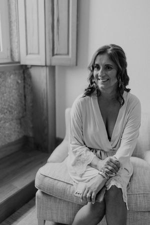 Bride laughing while talking to bridesmaids — authentic storytelling moment during destination wedding prep in Portugal.
