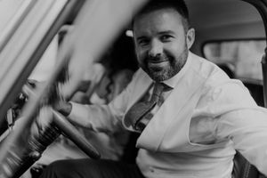 Groom looking out from the driver’s seat — relaxed black and white wedding portrait at The Astoria venue in Porto.