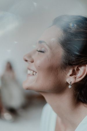 Bride smiling while getting makeup done — joyful wedding preparation moment in Porto, captured in natural light.