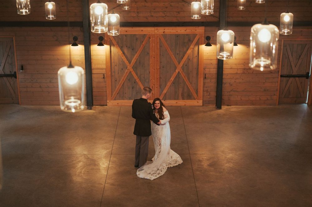 A romantic wedding dance captured in a rustic barn venue illuminated by glowing glass lanterns and wall sconces.
