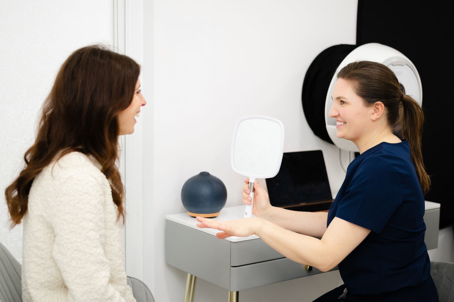 Healthcare professional showing medical equipment to patient during consultation in white medical office.