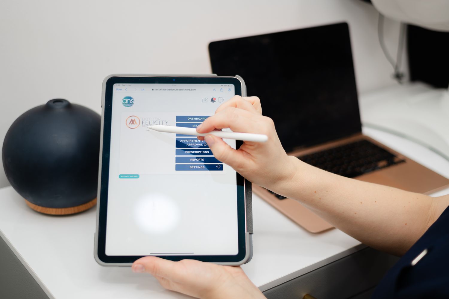 Hand touches tablet screen showing messaging interface while working at desk with black speaker in background.