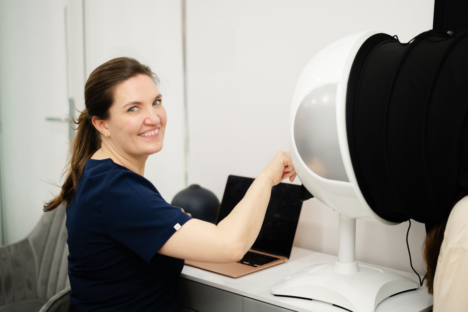 Healthcare worker operates advanced medical scanning equipment in a bright clinical setting.