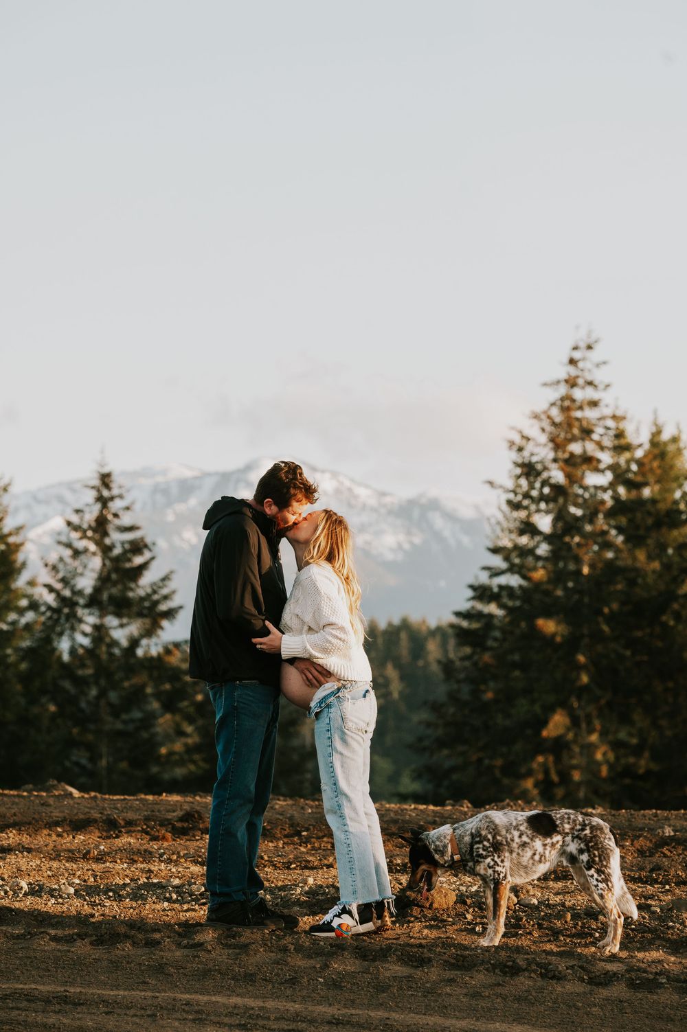 Maternity candid photography of couple kissing in front of beautiful mountain views on Vancouver island golden hour light photographer