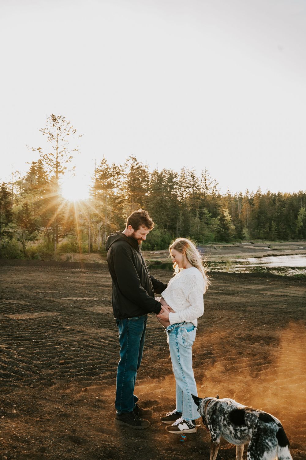 Maternity candid portrait couple embracing hill close to ocean dusty golden hour light beams Vancouver Island natural feeling photographer