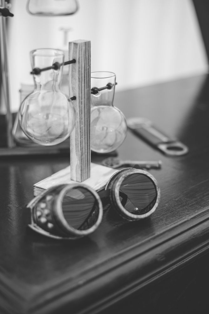 Vintage-inspired wooden stand displaying round glass bulbs and steampunk goggles in black and white.