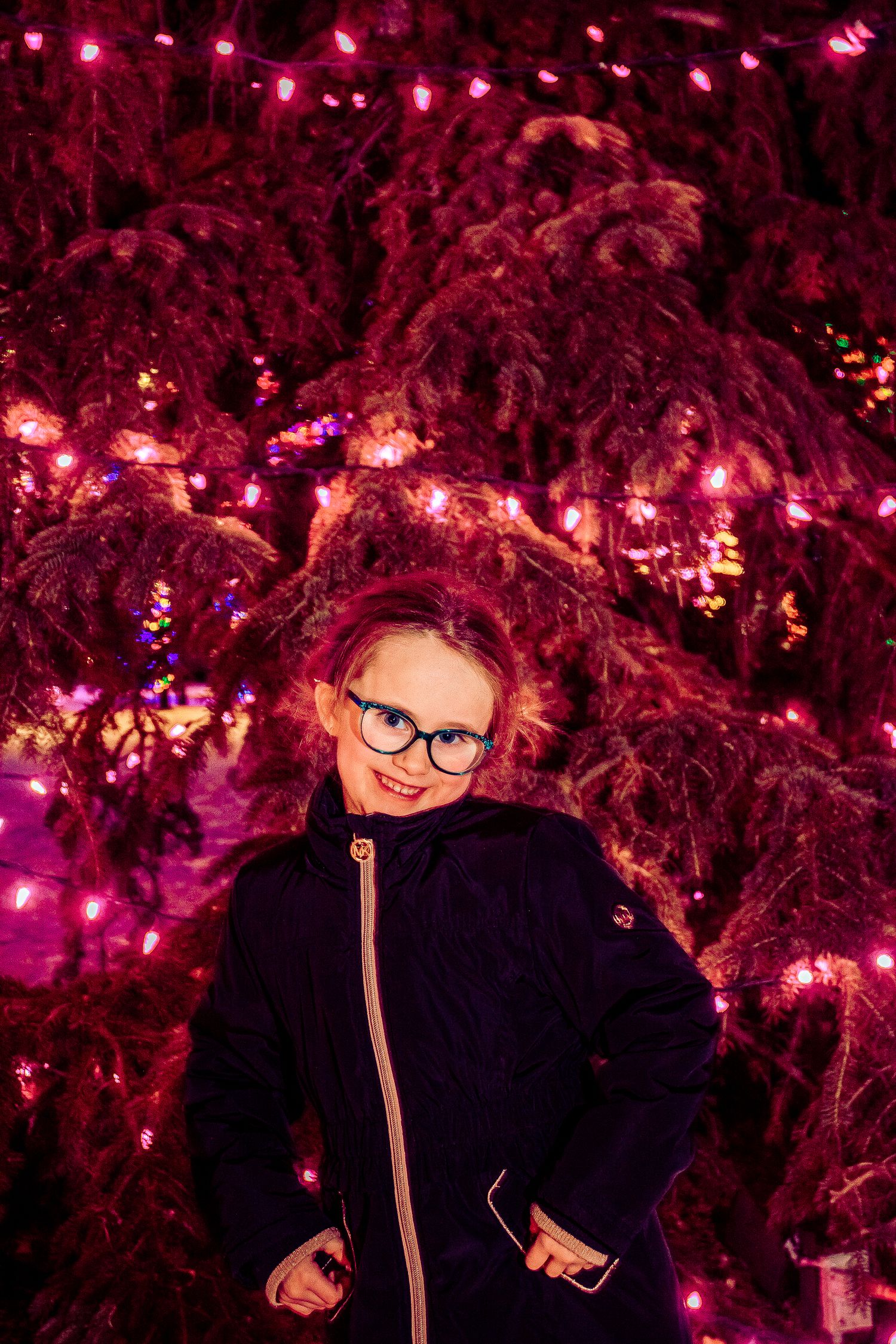 Winter portrait against a backdrop of magenta-lit holiday decorations in the snow.