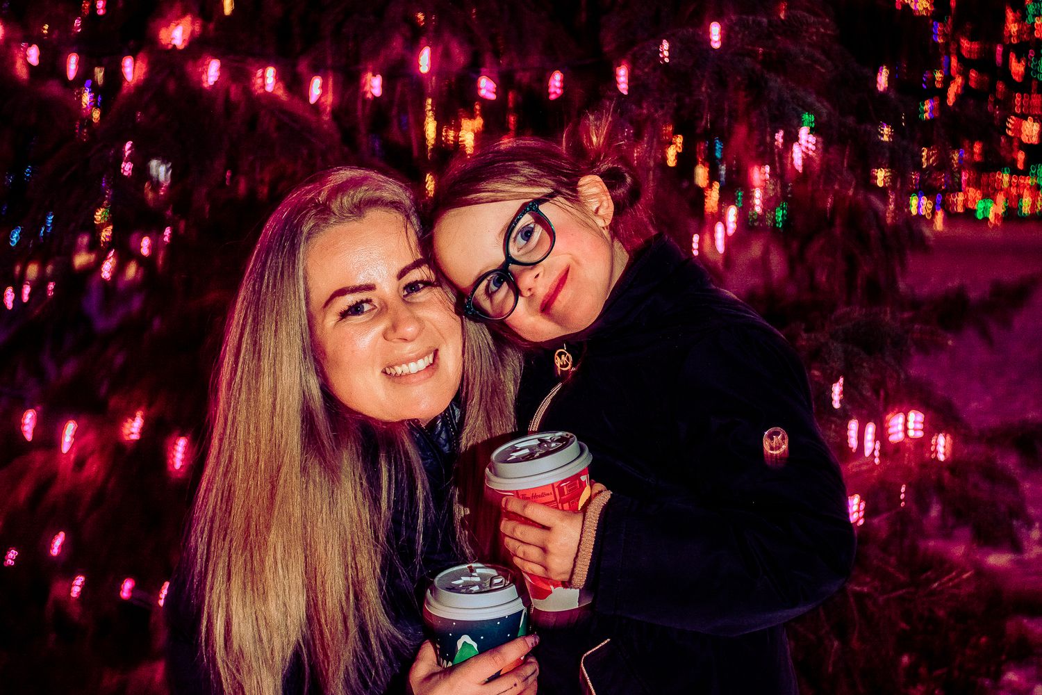 Cozy winter night portrait under glowing pink holiday lights.